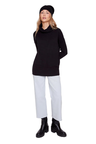 Person wearing a black sweater, white pants, and black boots on a white background