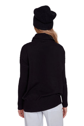 Person wearing a black sweater and hat on a white background