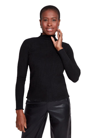 Woman wearing a black turtleneck and black pants against a white background