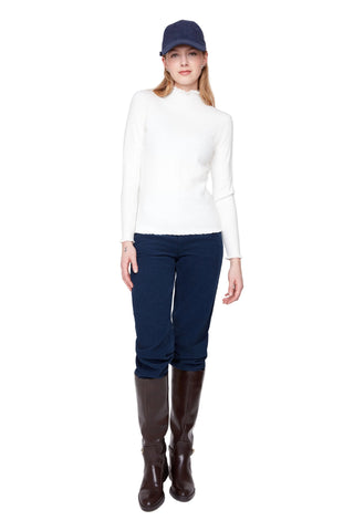Person wearing a white sweater, navy cap, blue pants, and brown boots on a white background