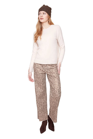 Woman wearing a beige sweater, patterned pants, and brown boots on a white background