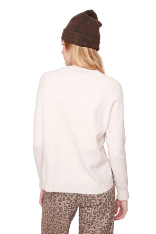 Person wearing a white sweater and leopard print pants with a brown beanie on a light gray background