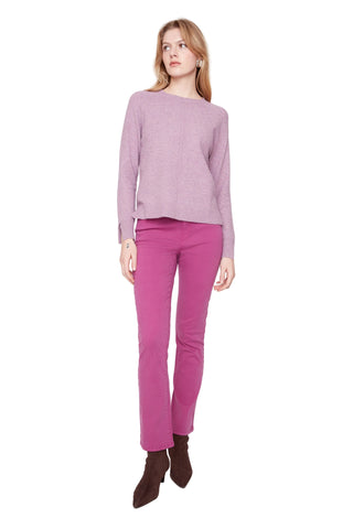 Woman wearing a light purple sweater and pink pants on a white background