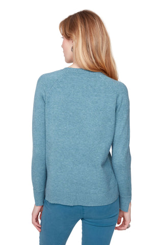 Woman wearing a blue sweater and pants against a white background