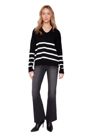 Woman wearing a black sweater with white stripes and gray pants on a white background