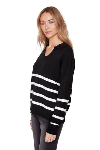 Woman wearing a black sweater with white stripes on a plain background