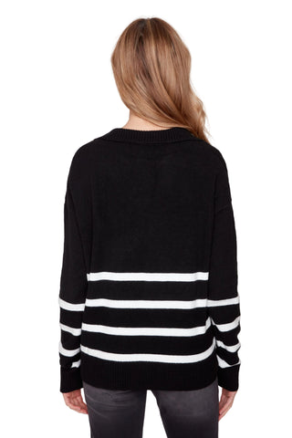 Person wearing a black sweater with white stripes on a plain background