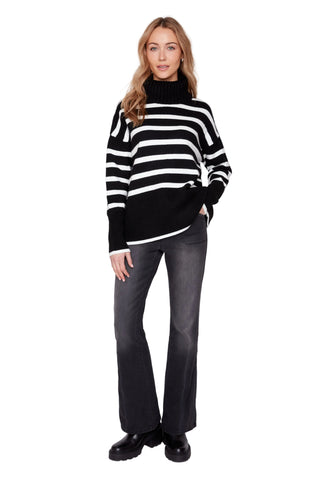 Woman wearing a black and white striped sweater with gray pants on a white background