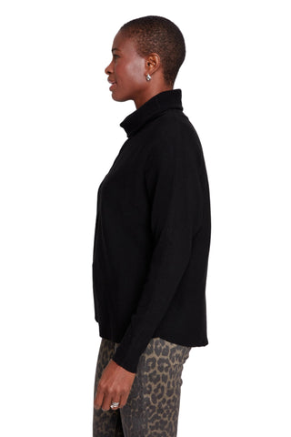 Person wearing a black turtleneck sweater with a plain background