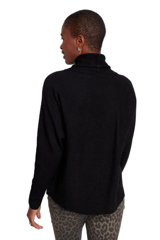 Person wearing a black turtleneck sweater with leopard print pants on a white background