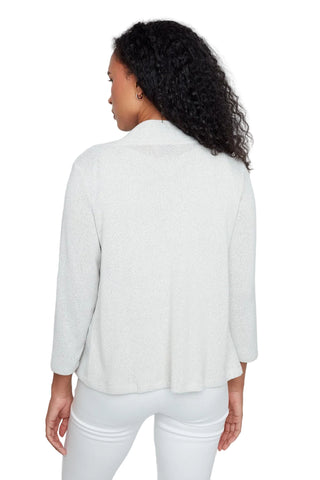 A woman with curly black hair is shown from the back wearing a light gray, textured three-quarter sleeve top and white pants against a plain white studio background.