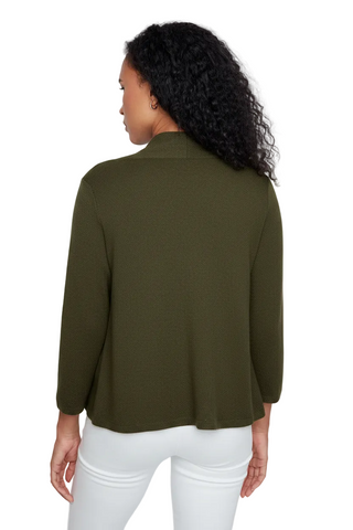 A woman shown from the back wearing a solid olive green long-sleeve top and white pants against a light gray studio background.