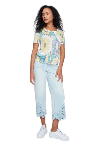 Woman wearing a floral top and light blue pants on a white background
