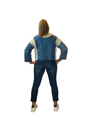 Person wearing a denim jacket and jeans standing in front of an Anne's on the Avenue sign.
