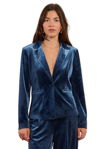 Woman wearing a blue velvet suit against a pink background