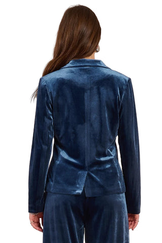 Blue velvet suit on a model against a beige background