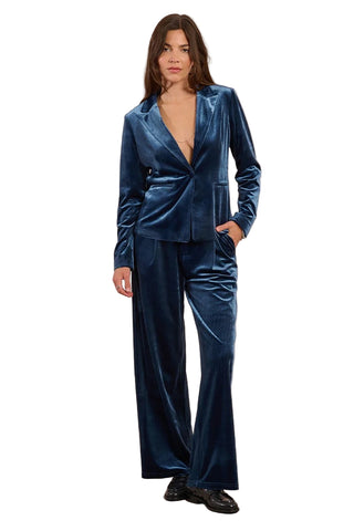 Woman wearing a blue velvet suit against a beige background