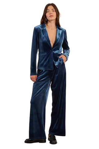 Woman wearing a blue velvet suit against a plain background
