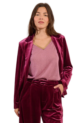 Woman wearing a burgundy velvet outfit against a pink background