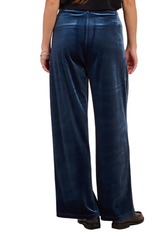Person wearing blue velvet pants on a beige background