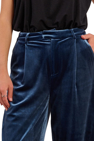 Navy velvet pants worn by a person on a plain background