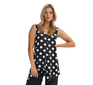 Woman wearing a black sleeveless top with white polka dots on a white background