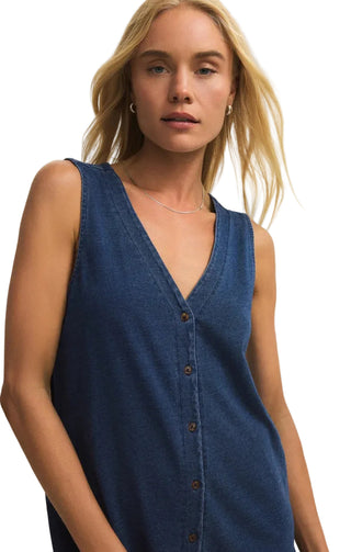 Woman wearing a blue sleeveless button-up dress against a plain background