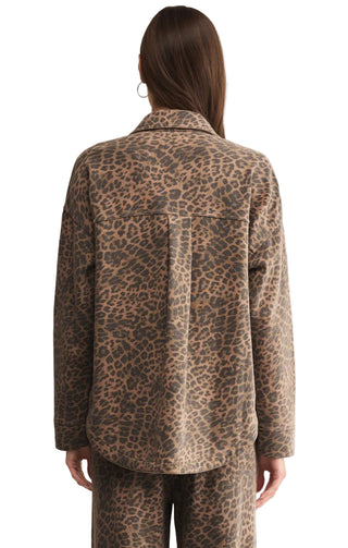 Person wearing a leopard print shirt and pants on a beige background