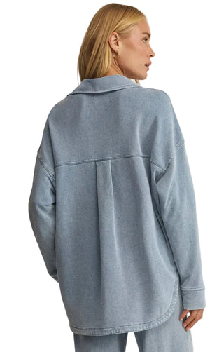 Person wearing a light blue denim jacket on a beige background