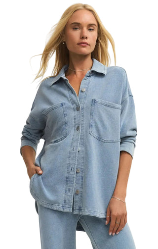 Woman wearing a light blue denim shirt against a plain background