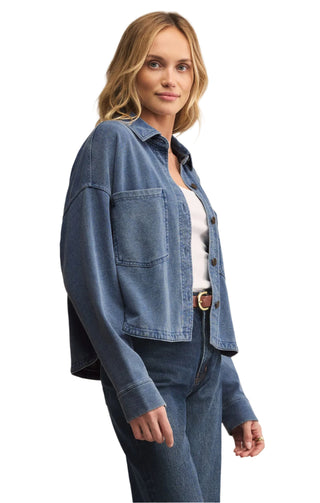 Woman wearing a blue denim jacket and pants on a beige background