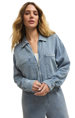 Woman wearing a denim jumpsuit against a plain background