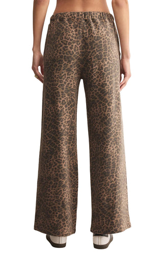 Leopard print pants worn by a person on a beige background