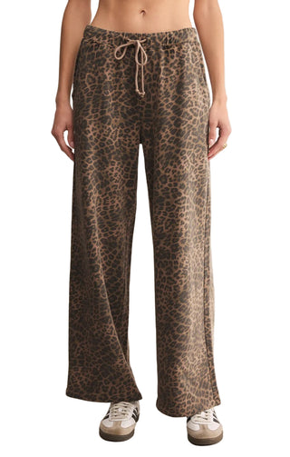 Leopard print pants worn by a person on a beige background