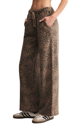 Leopard print pants worn by a person on a beige background