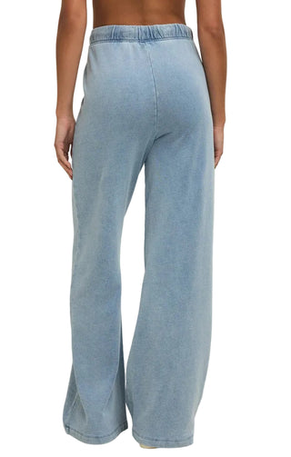 Light blue denim wide-leg pants worn by a person on a beige background