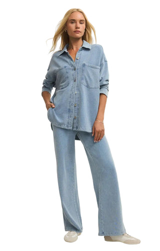 Woman wearing a light blue denim outfit on a plain background
