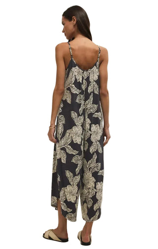 Woman wearing a floral jumpsuit on a plain background