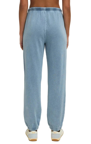 Light blue sweatpants worn by a person on a beige background