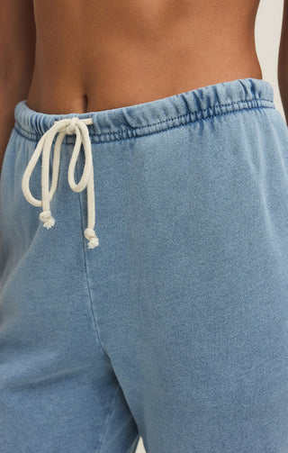 Blue sweatpants with a white drawstring on a neutral background