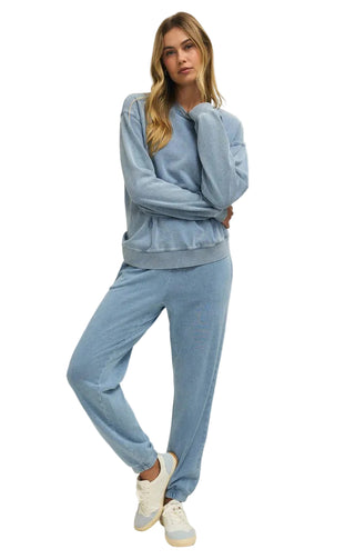 Woman wearing a light blue tracksuit on a plain background