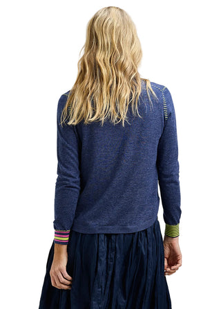 Person wearing a blue sweater and dark skirt on a plain background