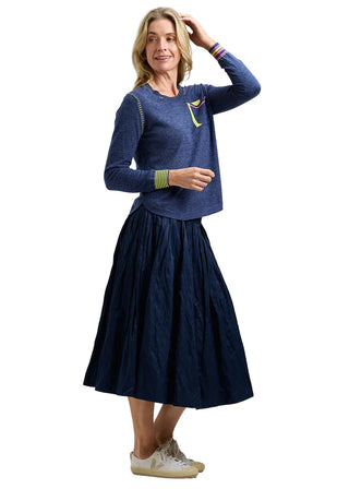 Woman wearing a blue sweater and navy skirt on a white background