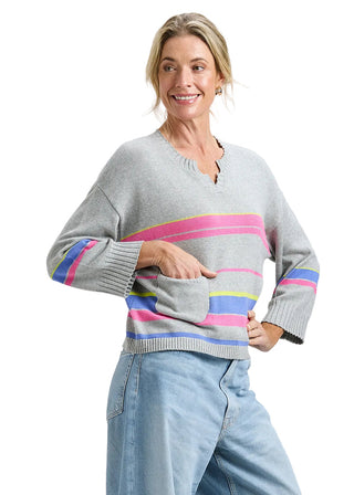 Woman wearing a gray sweater with colorful stripes on a plain background