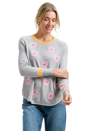 Woman wearing a gray sweater with pink floral patterns on a plain background