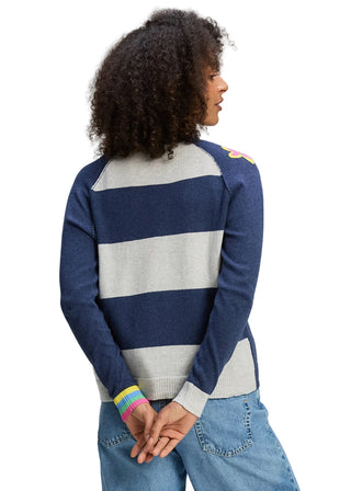 Person wearing a blue and gray striped sweater with colorful accents on a plain background
