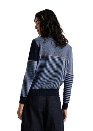 A woman shown from the back wearing a blue and navy striped knit sweater with a solid navy yoke and dark navy wide-leg pants, against a plain light gray studio background.