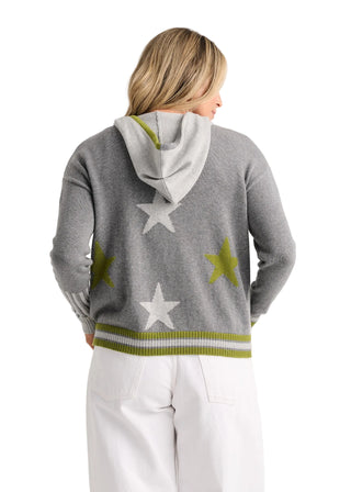 A woman shown from the back wearing a gray knit hoodie with white and olive green star patterns and striped trim, paired with white pants, against a plain light background.