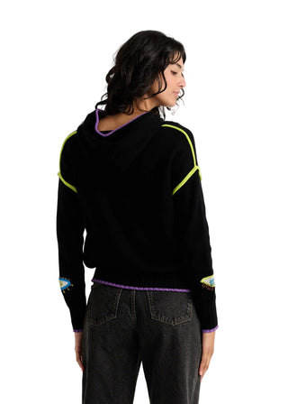 A woman shown from the back wearing a black knit hoodie with neon yellow-green stripe accents on the shoulders and sleeves, a purple inner hood lining, and dark gray jeans against a plain light background.