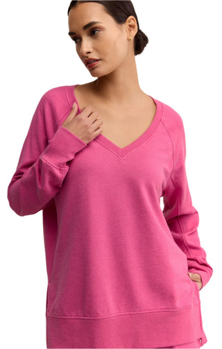 Woman wearing a pink long-sleeve top against a beige background